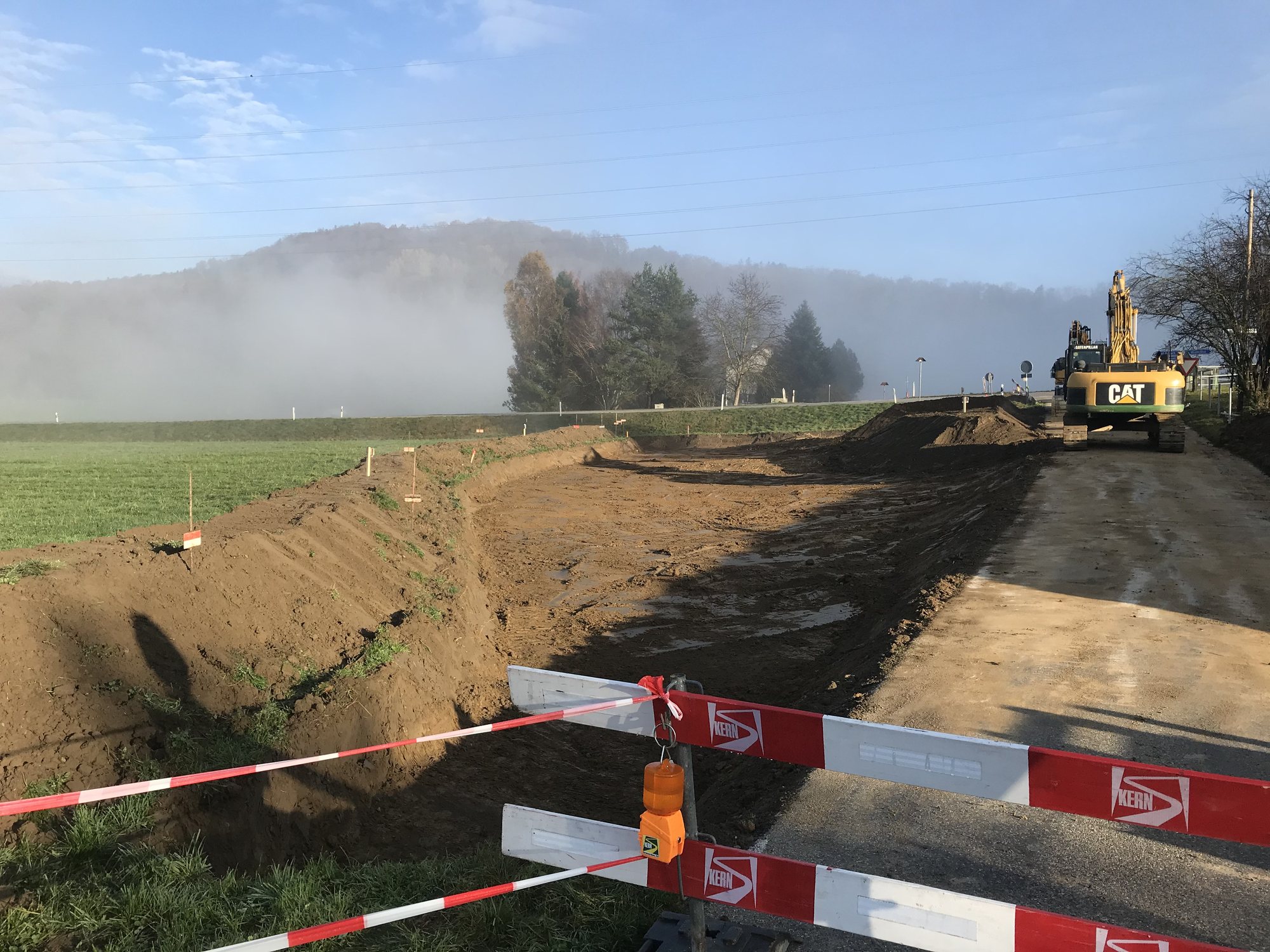Bagger beim Aushub im Morgennebel