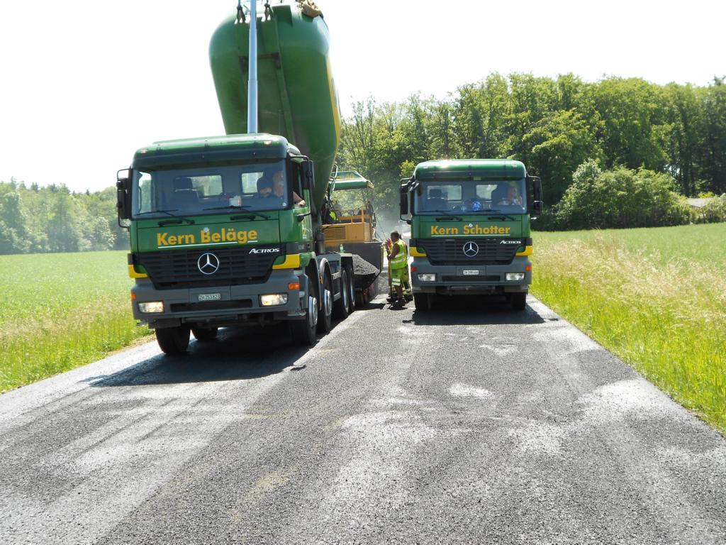 Zwei Lastwagen der Kern Strassenbau AG liefern Belag und Schotter an den Fertiger