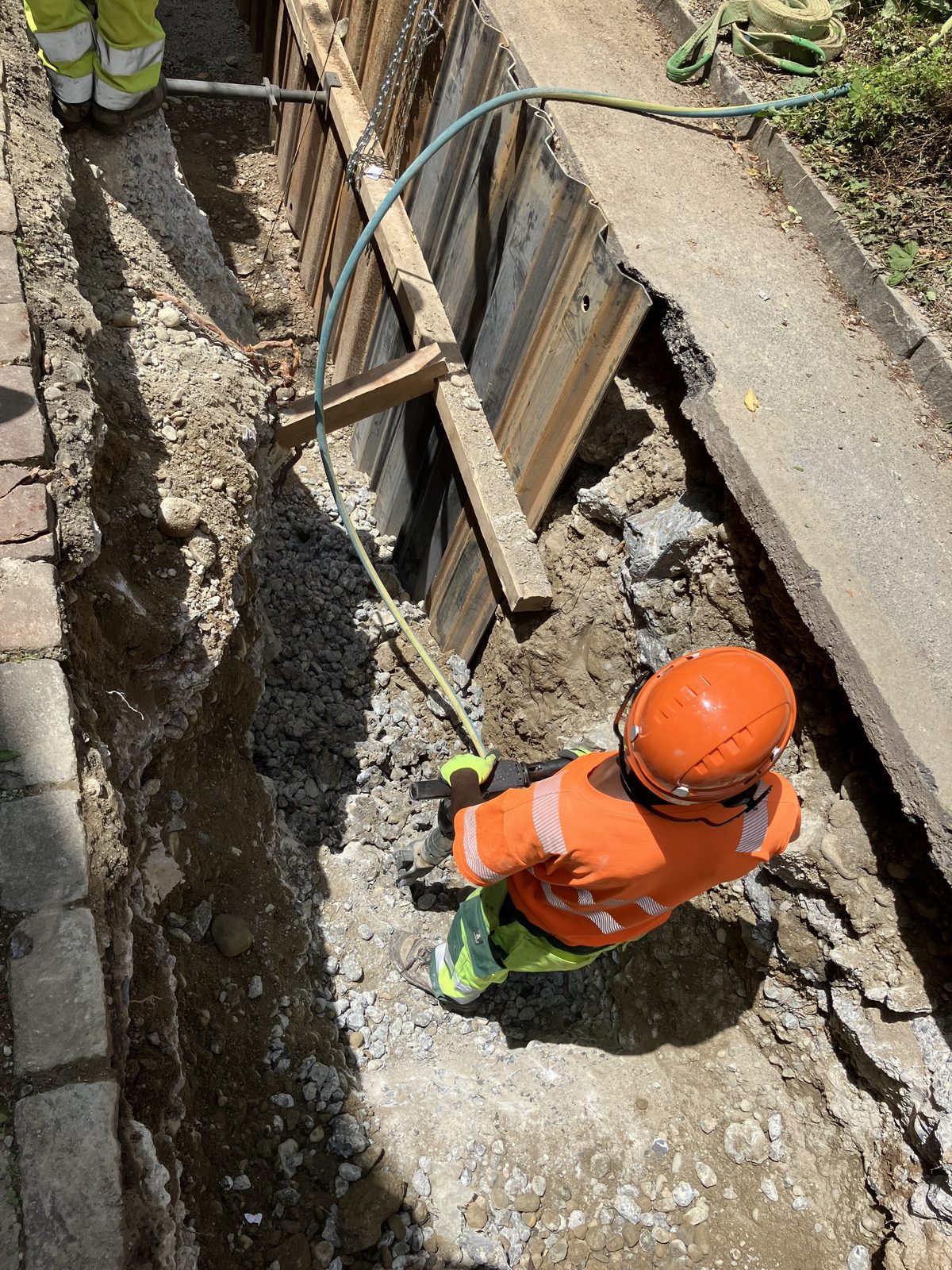 Mitarbeiter mit Helm bei der Arbeit im Graben