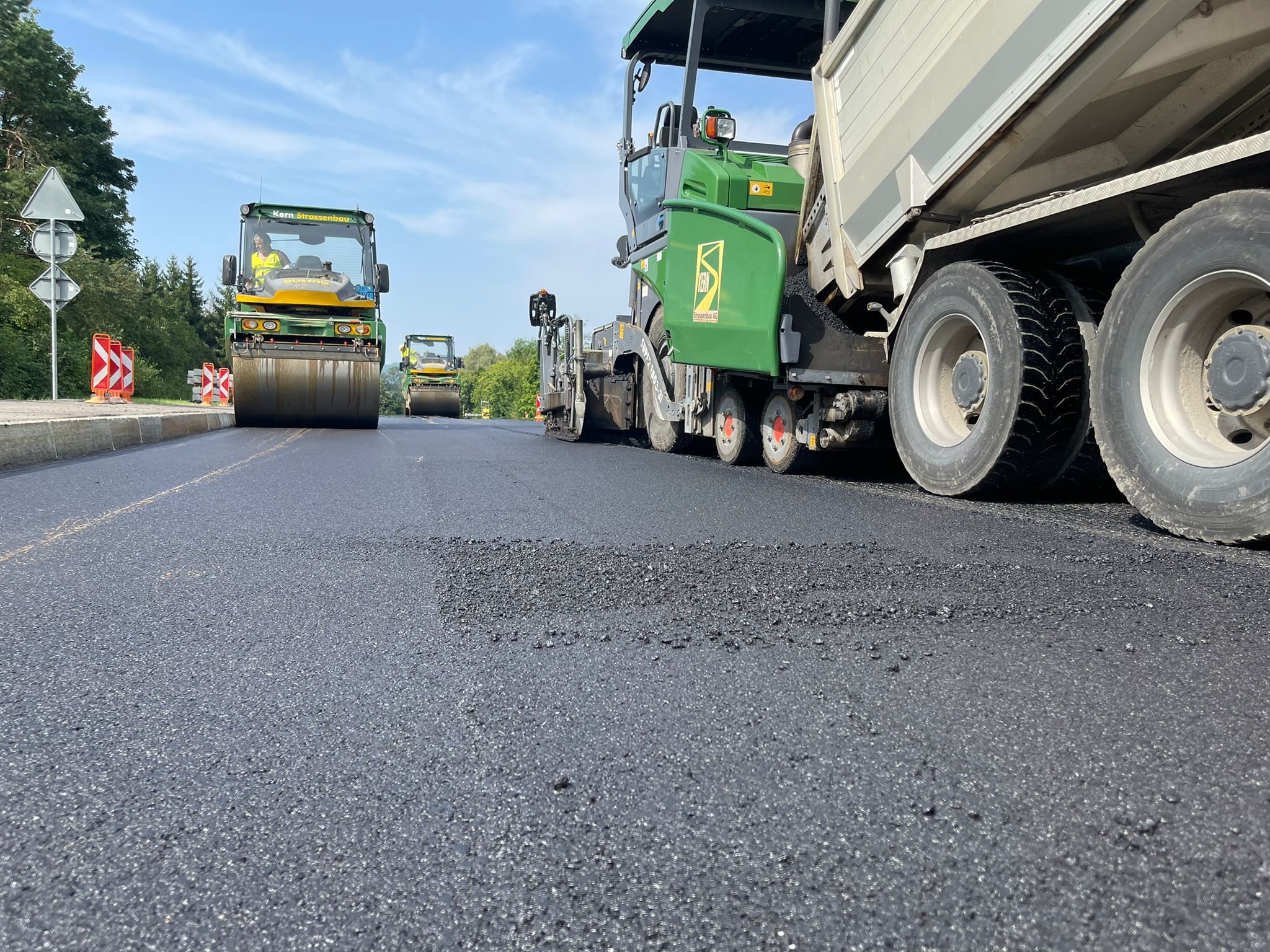 Zwei Mitarbeiter der Kern Strassenbau AG vor einem Bagger